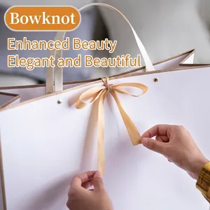 Elegant white paper gift bag with champagne ribbon bow and gold rivet details