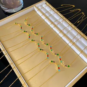 Vue détaillée de colliers arc-en-ciel dorés avec des lettres étincelantes en cristaux