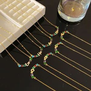 Vue détaillée de colliers en or avec des pendentifs alphabet en strass colorés.