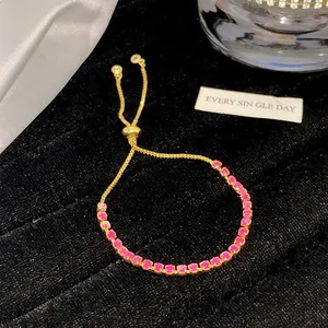 Nahaufnahme eines eleganten goldfarbenen Armbands mit funkelnden rosa Kristallen und Verschluss