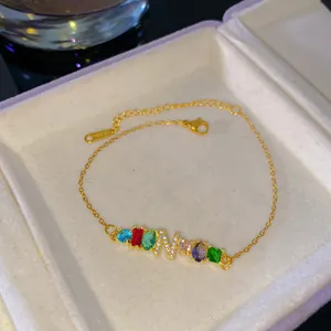 Elegante pulsera de oro con gemas de arcoíris y un colgante de cristal con la letra N