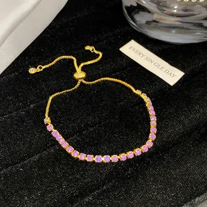Detail eines verstellbaren goldfarbenen Armbands mit lila Kristallen auf schwarzem Samt