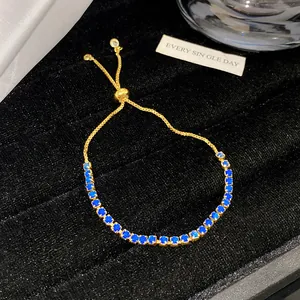Nahaufnahme eines goldfarbenen verstellbaren Armbands mit blauen Kristallen