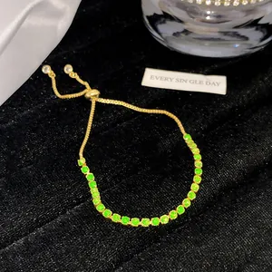 Detailansicht eines eleganten Goldarmbands mit grünen Kristallen auf schwarzem Samt.