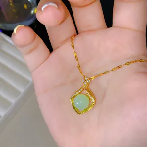 Gros plan d'un collier pendentif pochette dorée orné d'une perle verte et de cristaux