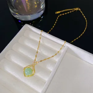 Gros plan d'un collier pendentif porte-bonheur avec perle verte et finition dorée chic.