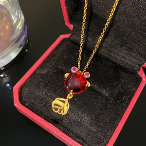 Détail macro d'un collier poisson rouge en or avec pendentif gemme rouge.