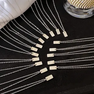 Détail de divers colliers en acier titane avec pendentifs gravés de lettres