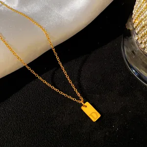 Gros plan d'un collier en acier titane doré avec pendentif rectangulaire et lettre D
