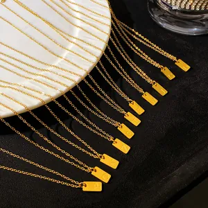 Détail de colliers en acier doré avec des pendentifs rectangulaires à initiales