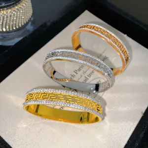 Nahaufnahme von Titanstahl-Armreifen mit klassischem Mäander-Muster und Glitzersteinen.