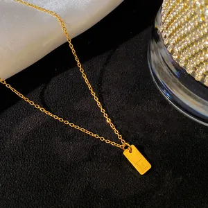 Gros plan d'un collier en acier titane doré avec un pendentif rectangulaire F.