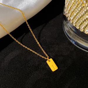 Gros plan d'un collier en acier titane doré avec un pendentif rectangulaire gravé