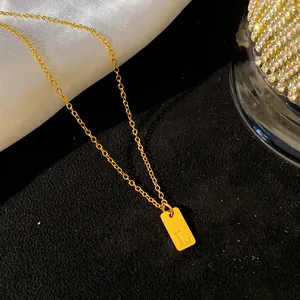 Gros plan d'un collier en acier titane doré avec un pendentif gravé de la lettre L
