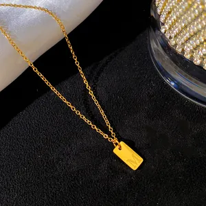 Gros plan d'un collier minimaliste en or avec un pendentif gravé de la lettre M.