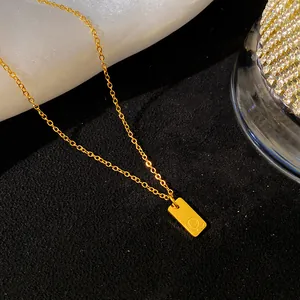 Vue macro d'un collier en acier titane doré avec un pendentif rectangulaire portant la lettre Q