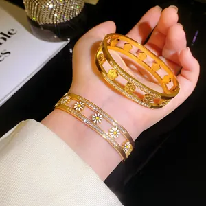 Detailweergave van vergulde roestvrijstalen armbanden met madeliefjes en klavers