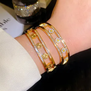 Detailopname van een gouden titanium stalen armband met elegante madeliefje- en klavermotieven