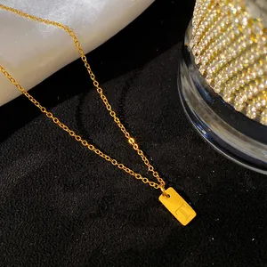 Gros plan d'un collier minimaliste en acier titane plaqué or avec la lettre T