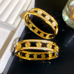 Close-up van elegante gouden titanium stalen armbanden met fonkelende madeliefjespatronen.