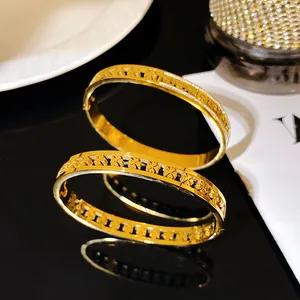 Close-up detail of a gold clover bangle with Greek key pattern and sparkling crystals