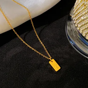 Détail macro d'un collier en acier titane doré avec pendentif gravé de l'initiale U