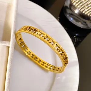 Detail view of a luxury golden stainless steel hollowed four-leaf clover pattern bangle