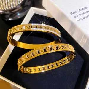 Close-up of gold-plated titanium steel bangles featuring Greek key and clover patterns