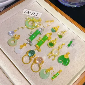 Detailed showcase of diverse gold-plated imitation jade pendants and rings on a display tray