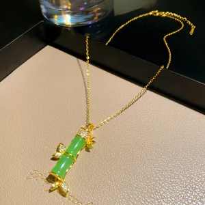 Dettaglio di una collana con pendente in bambù dorato, pietre verdi e accenti in cristallo