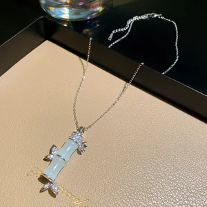 Primo piano di una collana con ciondolo in bambù argento con cristalli e pietra verde.