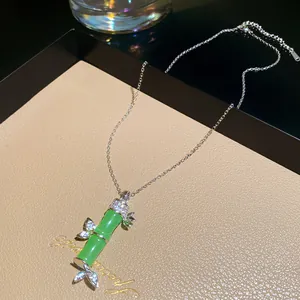 Dettaglio di un'elegante collana con pendente a forma di bambù verde e cristalli luminosi