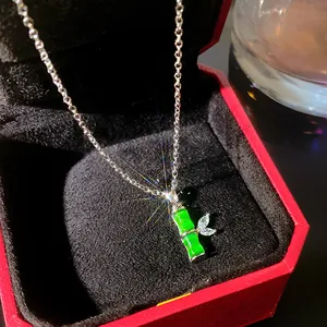Close-up of a silver necklace with a green bamboo jade-style pendant in a gift box