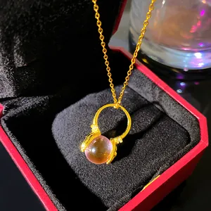 Close-up of a gold necklace with a pink bead pendant in a red luxury jewelry gift box.