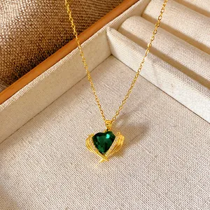 Detailed view of a gold heart necklace with a green gemstone and cubic zirconia accents.