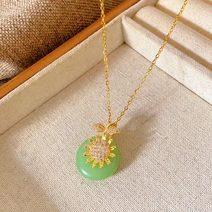 Detailed macro view of gold necklace with green stone pendant and zircon sun accent