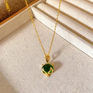 Close-up of a gold-plated necklace featuring a vibrant green gemstone fox pendant.
