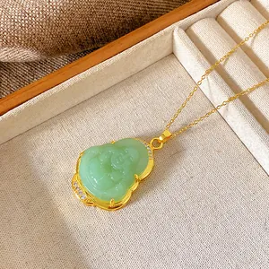 Close-up view of a gold-plated necklace with a green Buddha pendant in a luxury jewelry tray.
