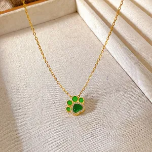 Detailed macro view of a gold-plated cat paw pendant necklace with green inlay