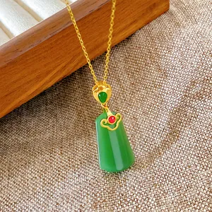 Detail of a vintage Chinese style necklace with a gold chain and green jade-like pendant