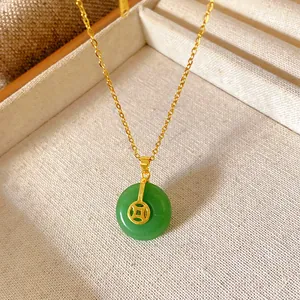 Close-up of a green doughnut jade pendant with a golden coin accent on a dainty chain.