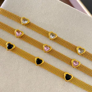 Macro detail of gold mesh bracelets featuring colorful heart-shaped crystal charms