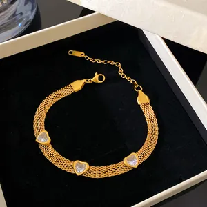 Detailed view of gold-plated mesh bracelet with three sparkling heart-shaped crystal charms.