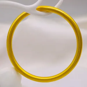 Primo piano di un bracciale a cerchio in oro opaco 18k minimalista su supporto bianco.