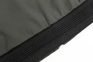 Detailed macro view of black ribbed knit hem and olive green woven fabric on men's jacket
