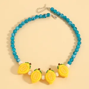Primo piano della collana di perle blu marmorizzate con ciondoli al limone.