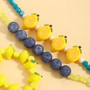 Primo piano dettagliato di perle di frutta in acrilico a forma di limone e mirtillo.