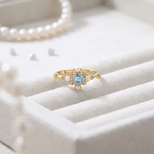 Elegante anello in argento sterling dorato con topazio azzurro e perle, design fiocco di neve.
