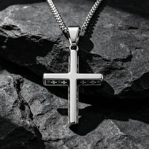 Collar con colgante de cruz de acero de titanio pulido sobre fondo de piedras oscuras