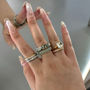 Close-up of stacked stainless steel rings featuring natural stone and clear crystal details